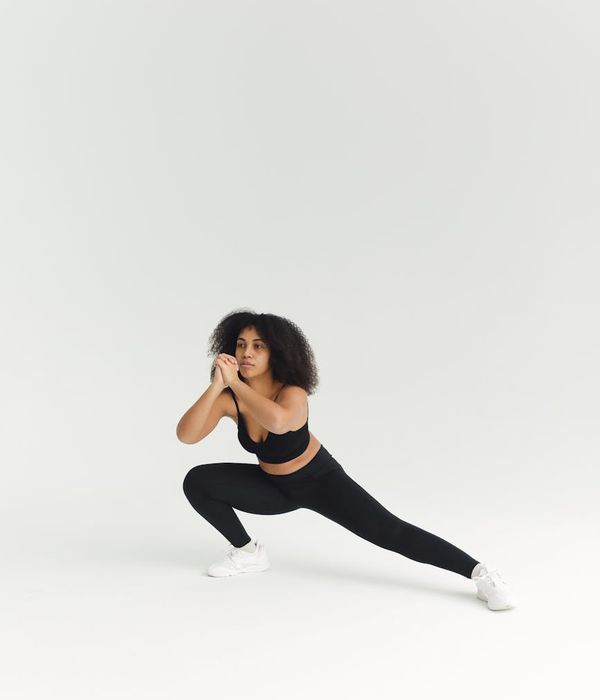 Woman performing a dynamic stretching exercise in a minimalist room.